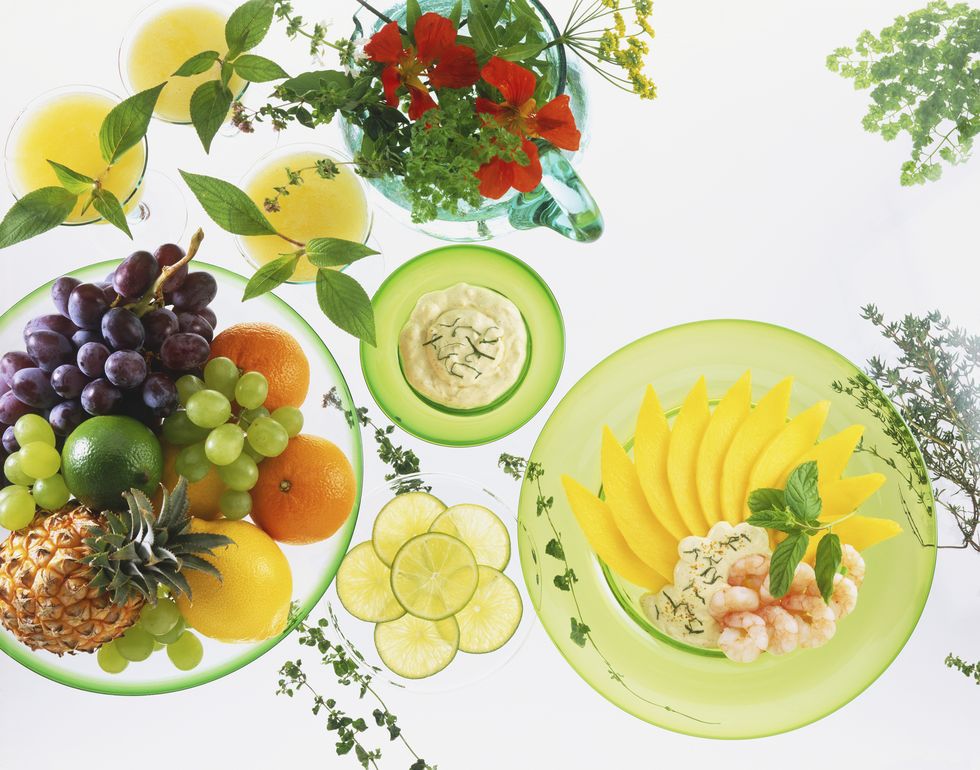 Bowls of fresh fruit, lime slices, herbs and dips, and a dish of sliced mango and peeled prawns