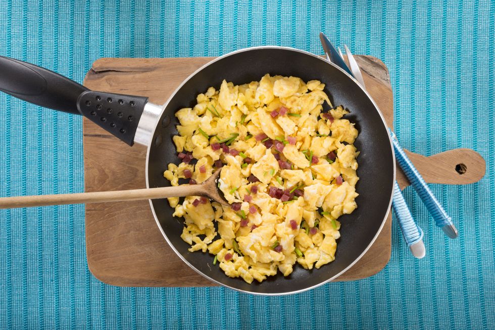Scrambled eggs with ham cubes in frying pan