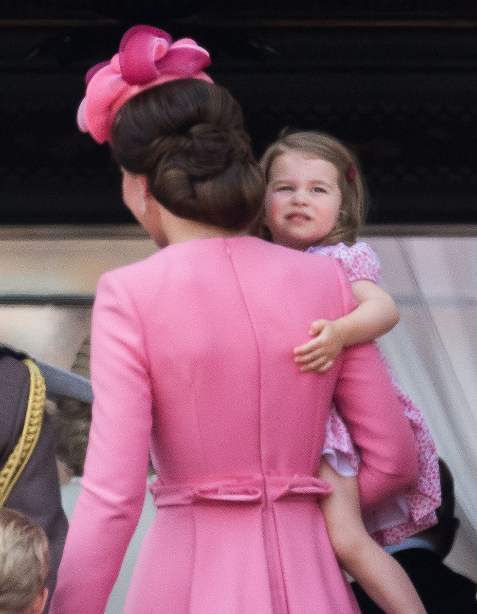 Di spalle Kate Middleton con in braccio la pricipessa Charlotte entrambe con un abito rosa