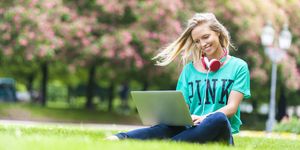 Una ragazza studia e lavora al computer in un parco durante l'estate