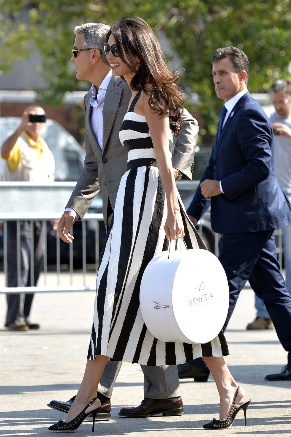 George Clooney (L) and his Lebanon-born British fiancee, Amal Alamuddin (C) holding a bag bearing the logo A&G (Amal and George ) arrive at Venice's Piazzale Roma in Venice on September 26, 2014, on the eve of their wedding. The party of the year is happening here: the fresco-adorned Aman hotel on Venice's Grand Canal is feverishly preparing for George Clooney's wedding to Amal Alamuddin, his Lebanon-born British fiancee. Hollywood stars and the world's paparazzi have already begun arriving for the nuptials of the world's most sought-after catch, who will, sources said, celebrate with 136 guests at the exclusive seven-star hotel in the 450-year-old Palazzo Papadopoli. AFP PHOTO / ANDREAS SOLARO        (Photo credit should read ANDREAS SOLARO/AFP/Getty Images)