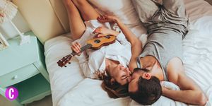 Una coppia che gioca sul letto suonando una chitarra