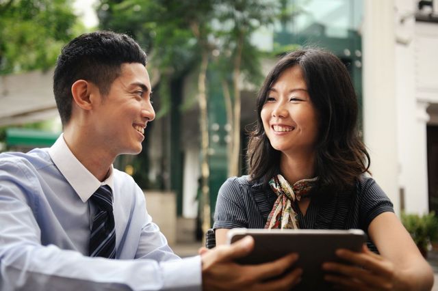 smiling couple using tablet outside