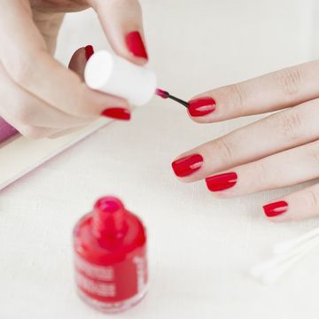 赤いマニキュアを塗る女性の手