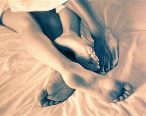 ベッドで絡み合う男女の足