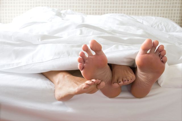 ベッドの上で絡み合う男女の足