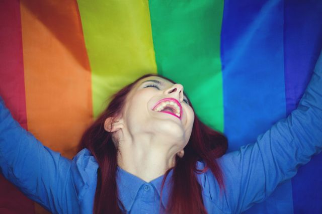 LGBTの象徴レインボーの旗を笑顔で広げる女性