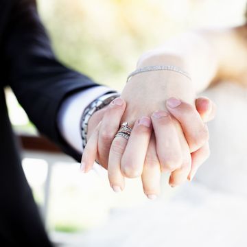 婚約指輪の光る手を繋いでいるカップルの手元