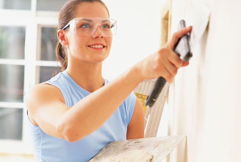 woman adding spackle to a wall