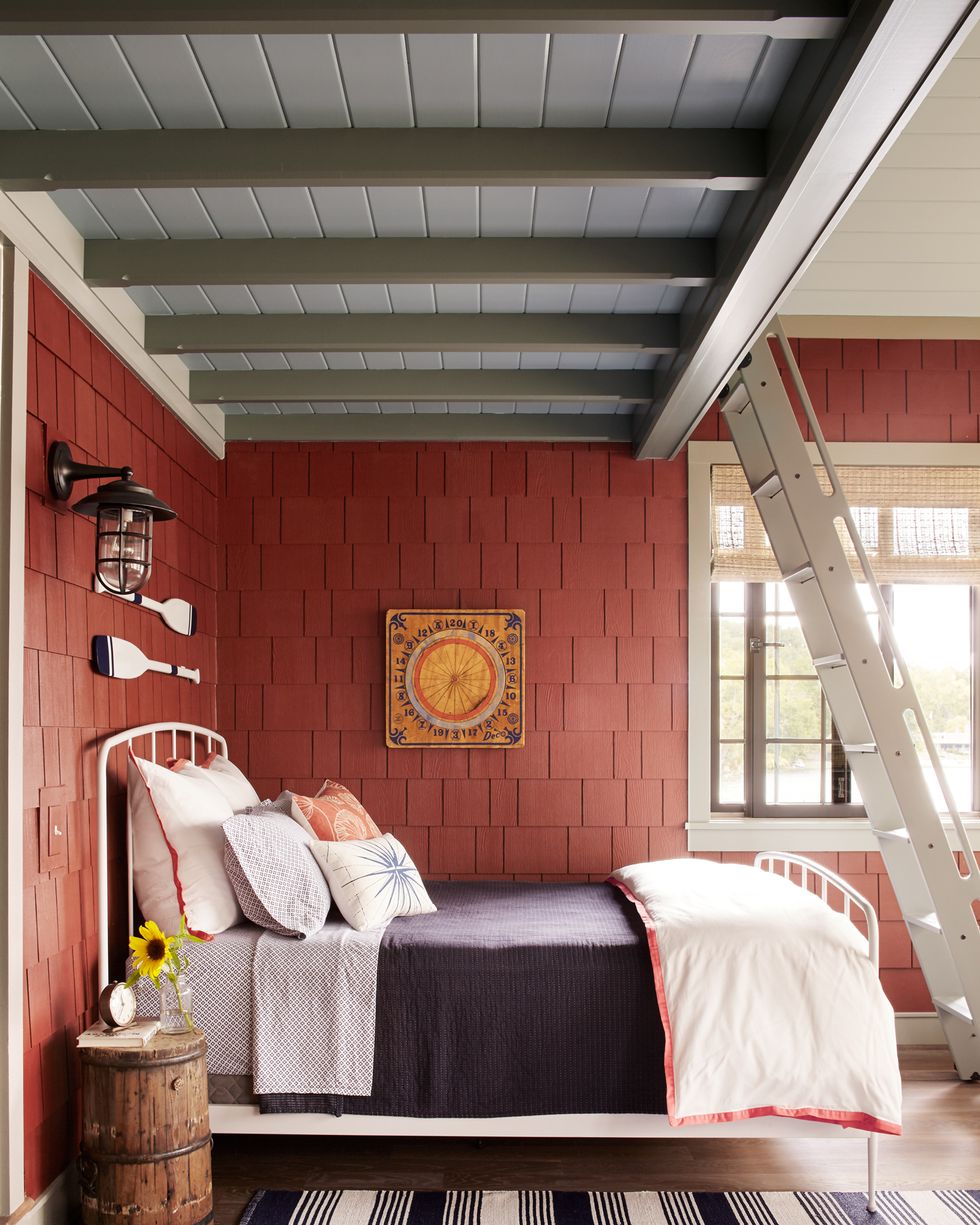 lake house bedroom with red shingled wall and white iron bed