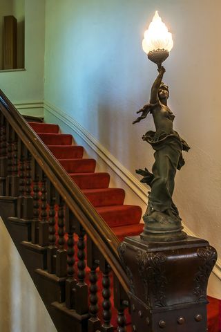 Stairs, Property, Bronze sculpture, Handrail, Baluster, Sculpture, Molding, Light fixture, Wood stain, Bronze, 