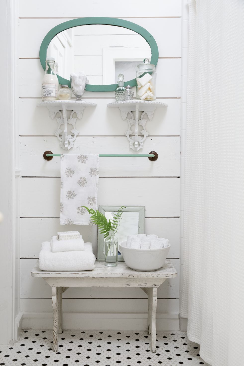 white shiplap farmhouse bathroom with corbels on the wall and a bench on the floor