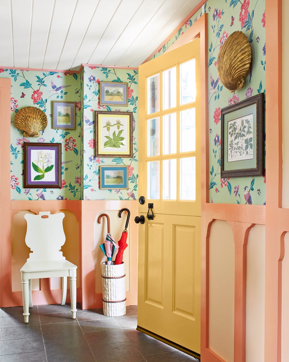 a colorful entryway that has peachy toned wainscoting and floral wallpaper