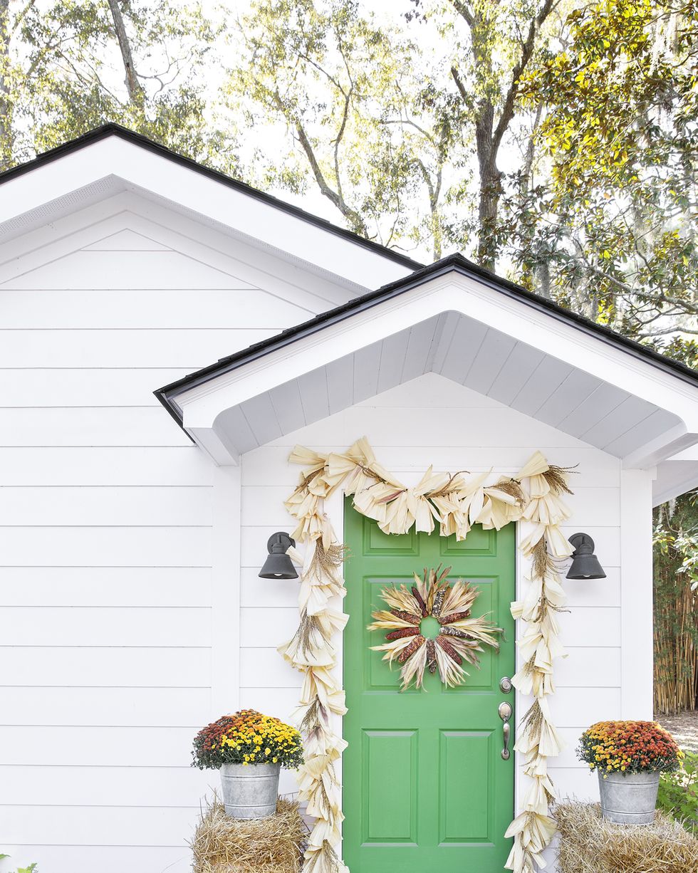 fall porch decorating ideas corn husk wreath and garland over green door