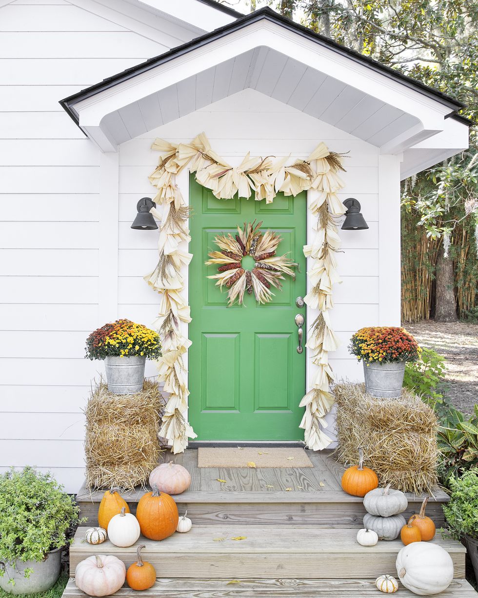 fall porch decorating ideas corn husk wreath and garland over green door