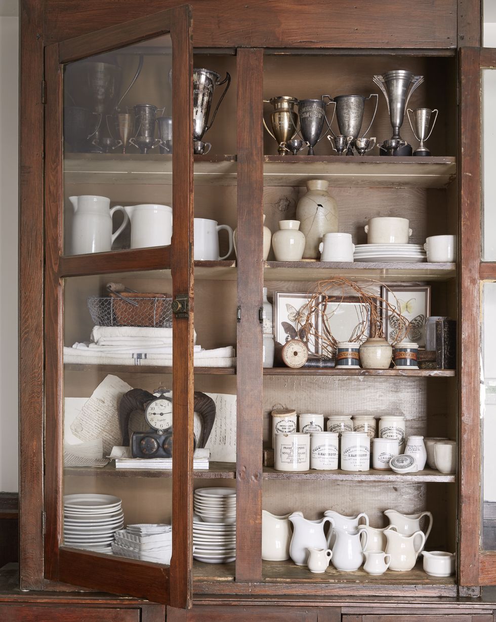 cupboard filled with collections of white ironstone and silver trophies