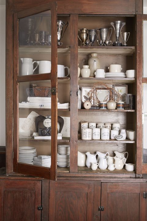 cupboard filled with collections of white ironstone and silver trophies