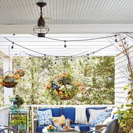 fall porch with blue and gray lunge furniture, large hanging baskets filled with pumpkins and fall flowers