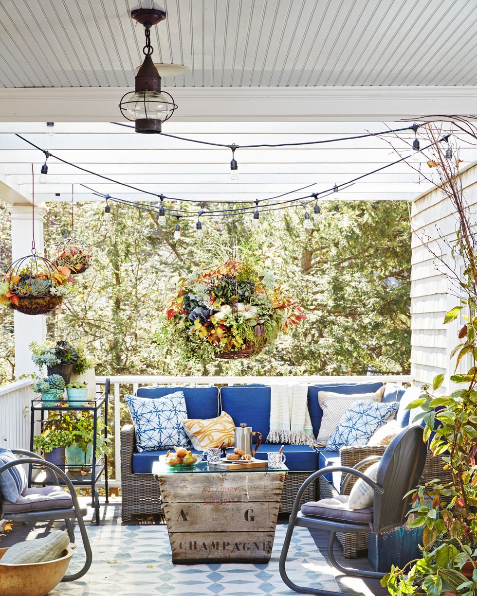 fall porch with blue and gray lunge furniture, large hanging baskets filled with pumpkins and fall flowers