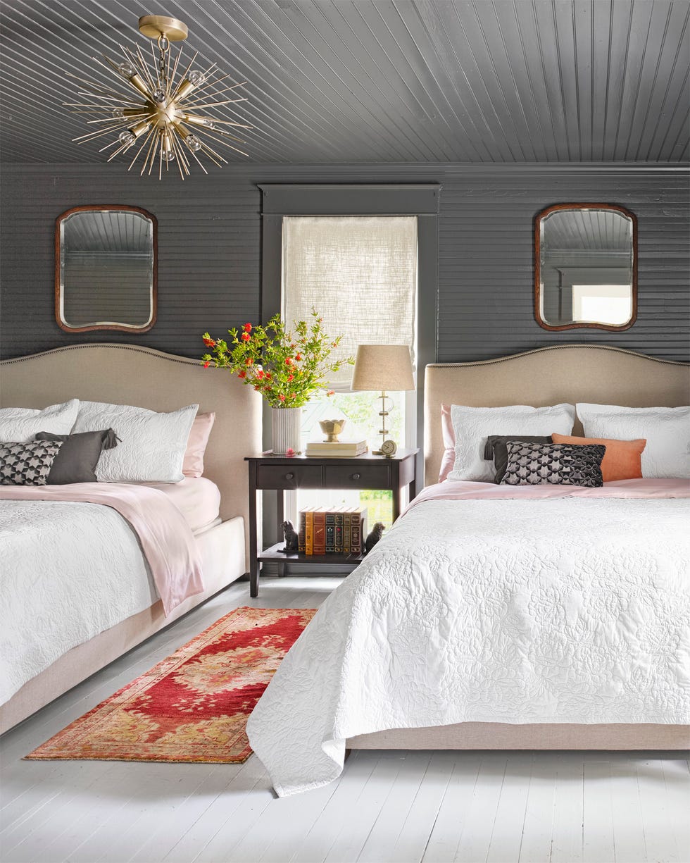 a dark gray bedroom with two upholstered beds topped with white coverlets