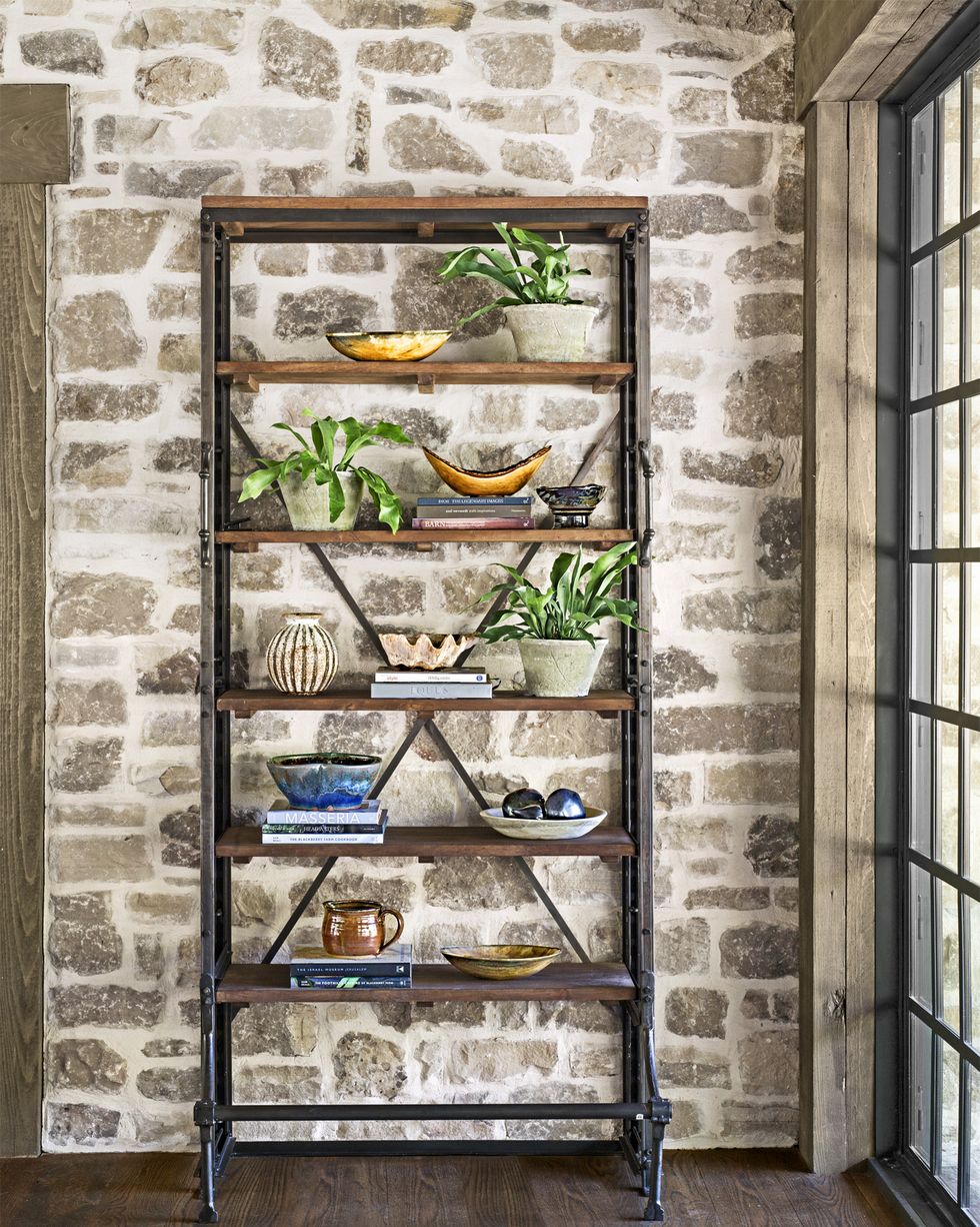 iron and wood bookshelves against stone wall