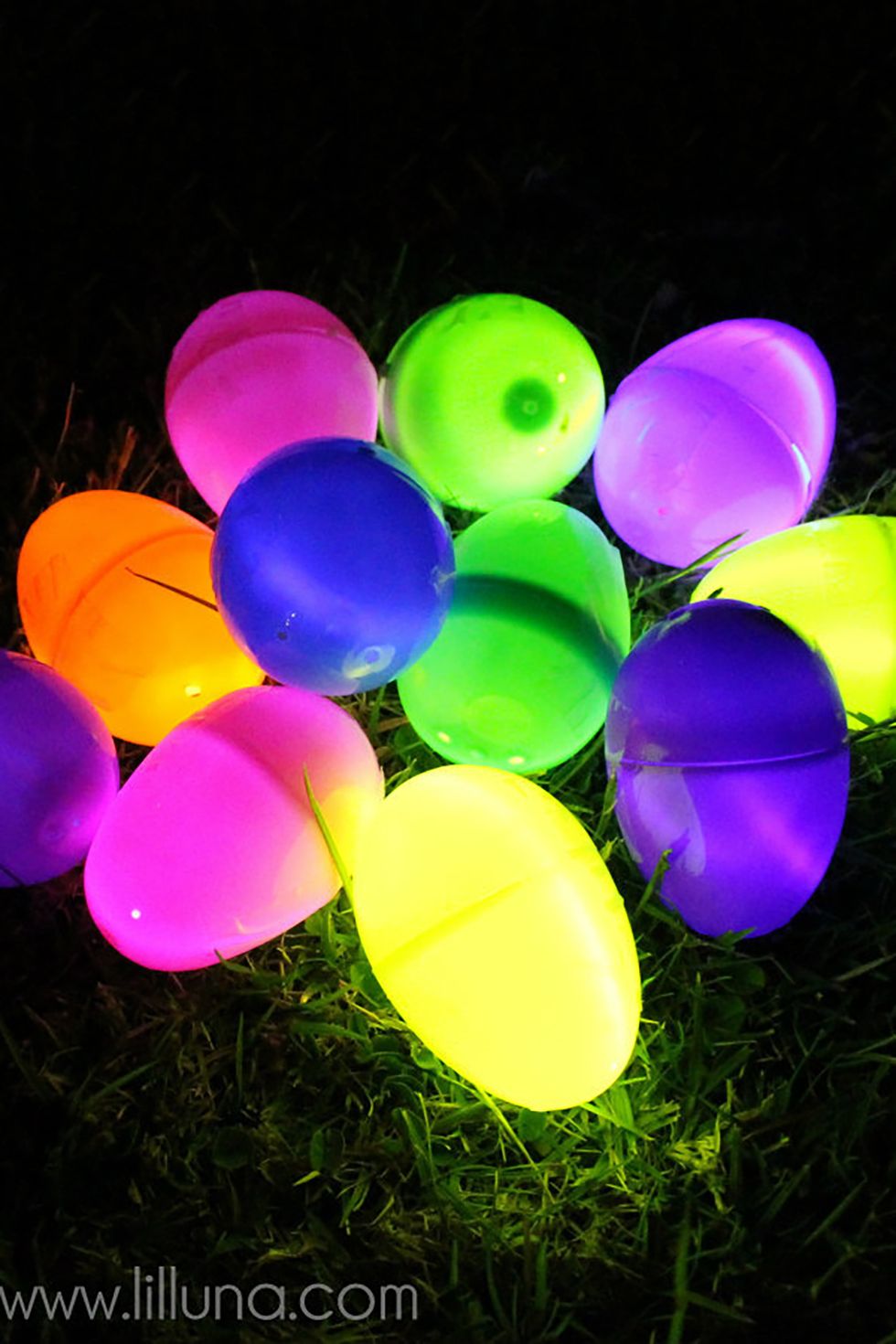 pink, yellow, green, orange, and purple easter eggs glowing in the grass at night for adult easter egg hunt