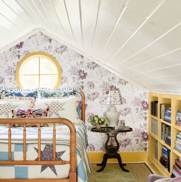 bedroom with purple floral wallpaper, green rug, quilted bedding, and yellow shelves