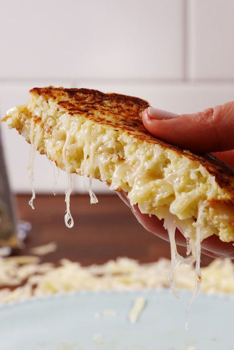 hand holding grilled cheese made from cauliflower patties instead of bread, oozing melted white cheddar