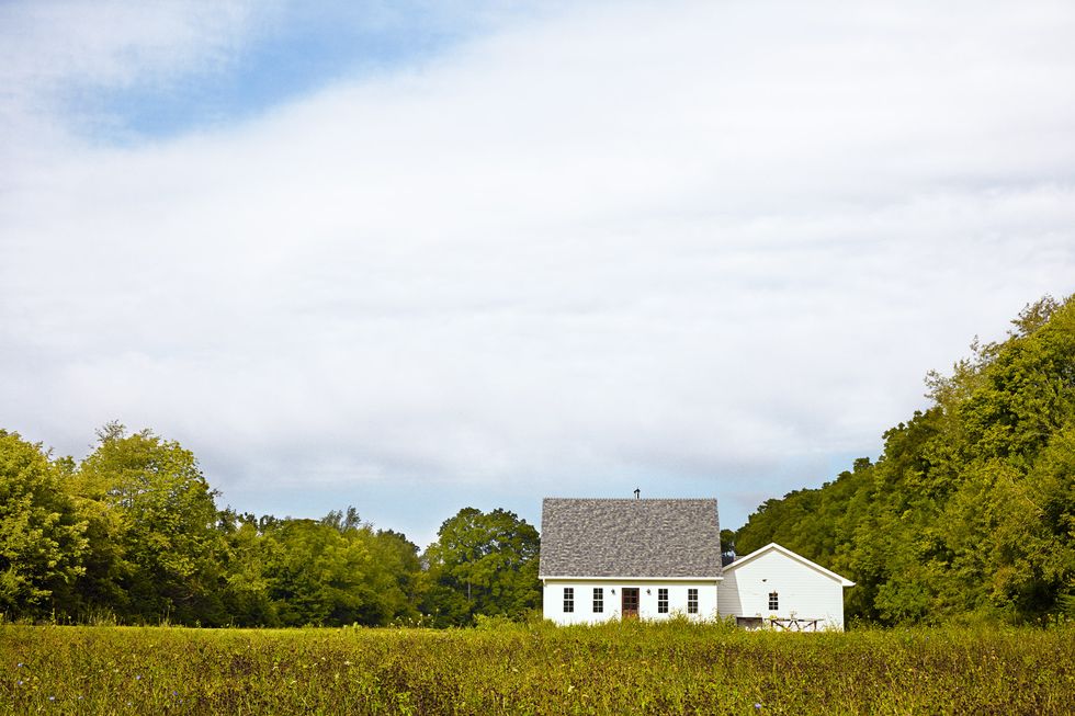 tiny white farmhouse in green landscape