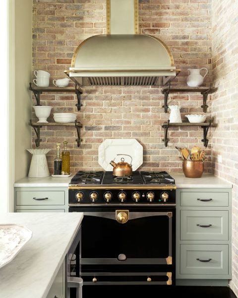 green kitchen cabinets with a black stove and brick backsplash