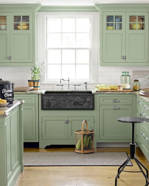 a kitchen with green upper and lower cabinets and a black slate chalkboard like sink