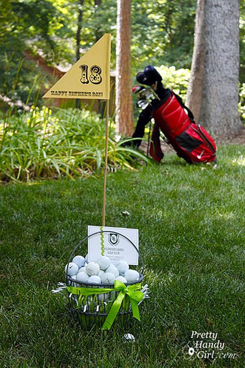 Golf-Themed Father's Day Gift Basket wire basket filled with faux grass, golf balls, a gift certificate to a golf club, and an 18th hole sign reading happy father's day