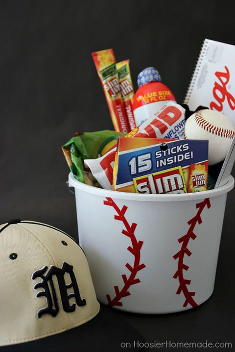 Father's Day Gift Basket - Baseball Fanatic Bucket white bucket decorated with red seams to resemble a baseball filled with snacks, sunscreen, a baseball, and a team cap