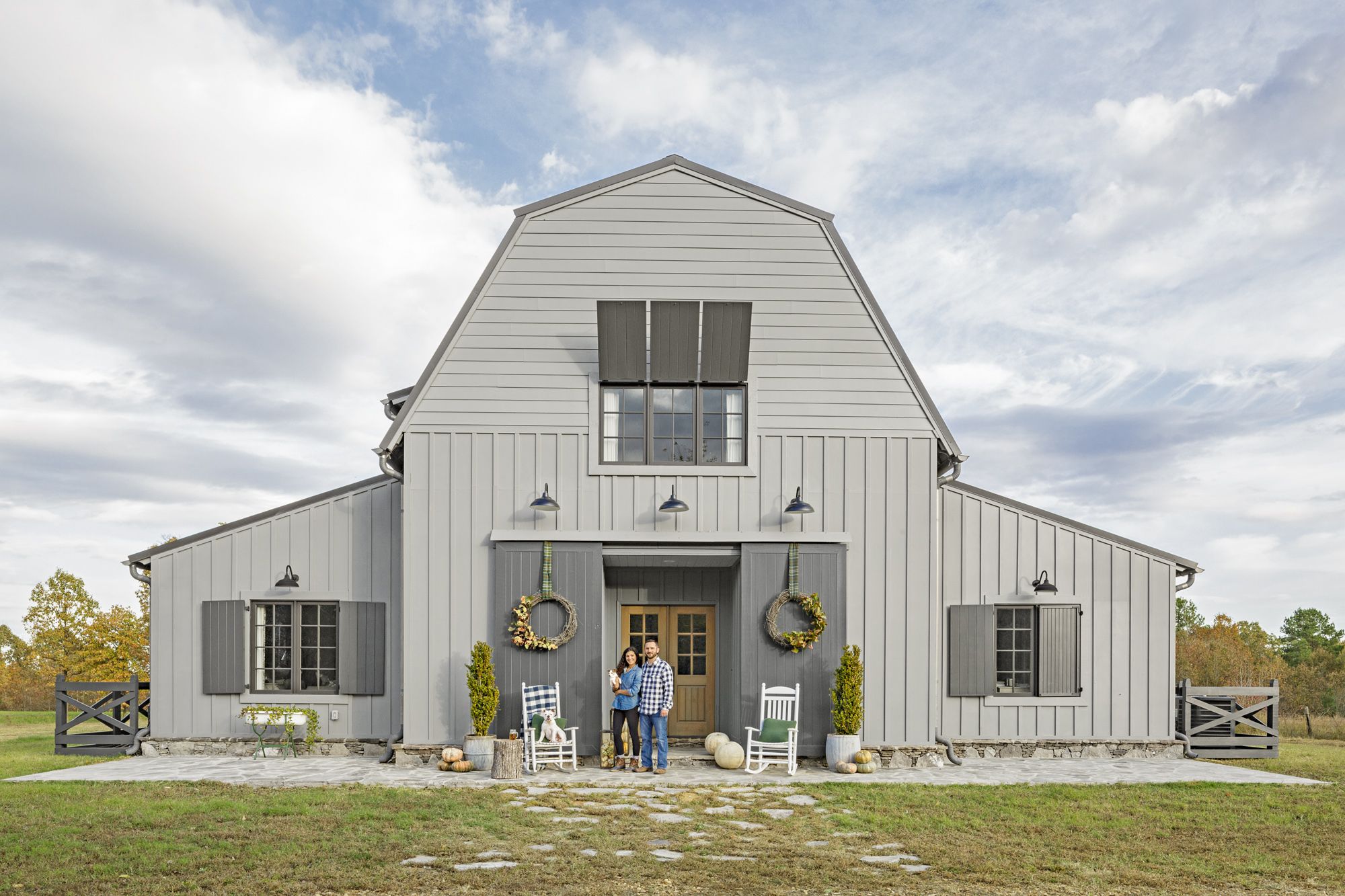 Picture of a barn with a man and a wife in front of it