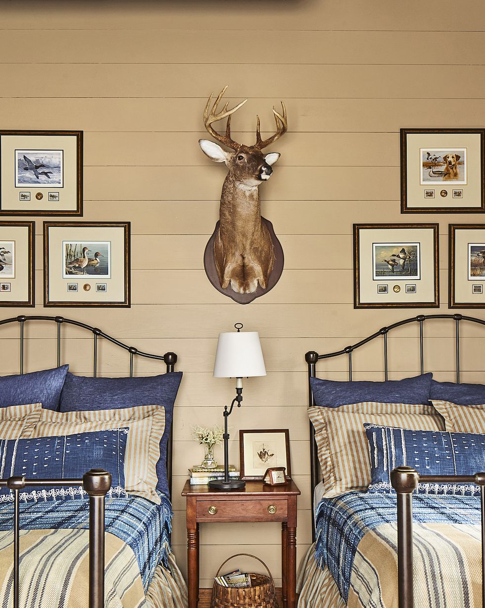 two twin beds in beige and blue with a deer head hanging on the wall above