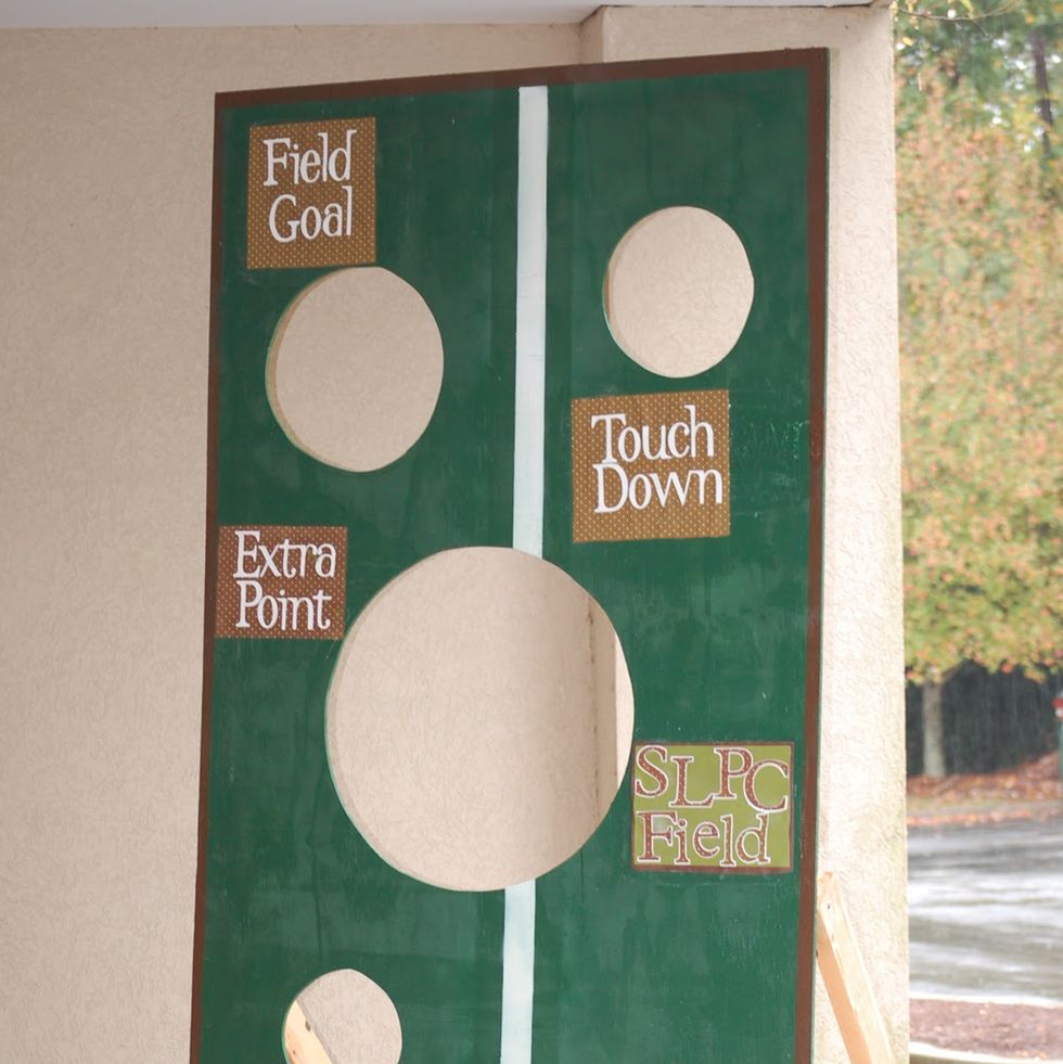 upright wooden football toss game with several various sized holes