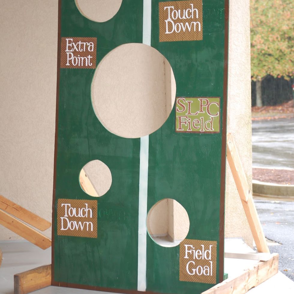 upright wooden football toss game with several various sized holes