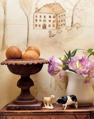 mural with new england scene behind a table with vase animal figurines and urn