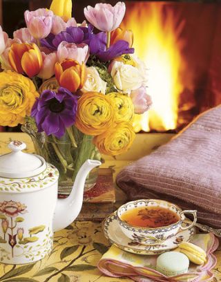 flowers and tea set in front of a fire