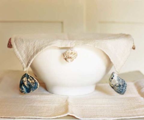 an off white linen bowl cover on top of white bowl with shells sewn on sides to anchor