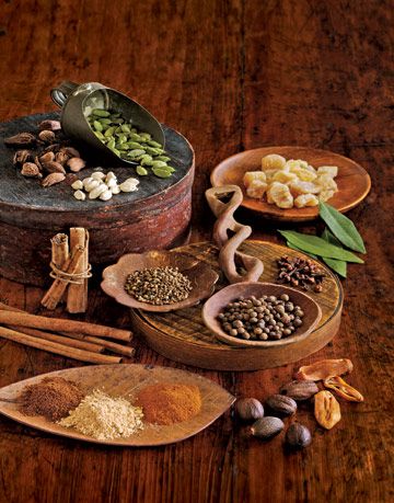 spices and beans in wooden dishes on a wood surface