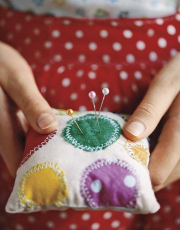 hands holding a small polka dot pin cushion