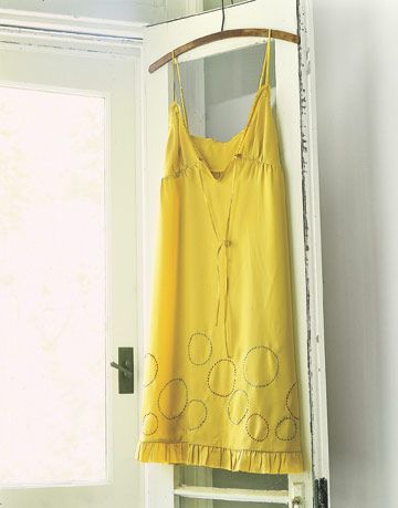 yellow dress with sewn polka dots on the bottom hanging from a door