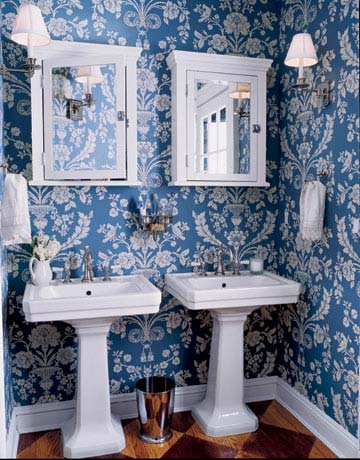 twin white pedestal sinks in blue and white floral wallpapered room