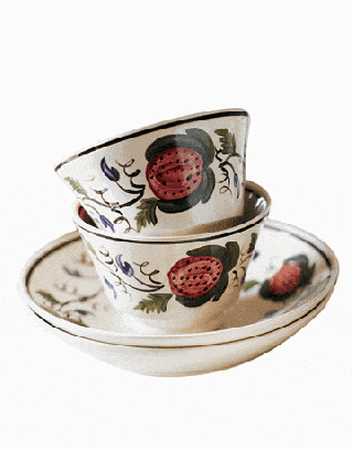 two ceramic cups stacked on a saucer with strawberry pattern