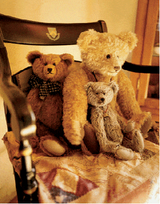 three different sized teddy bears in a wooden chair