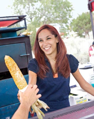 woman holding grilled corn