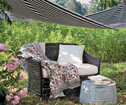 faux-wicker love seat with quilt under an awning