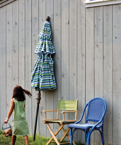 blue chair and green chair with umbrella leaning against wall