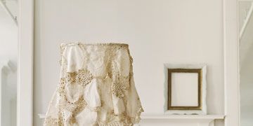 A white lamp with a lampshade covered in draped doilies.